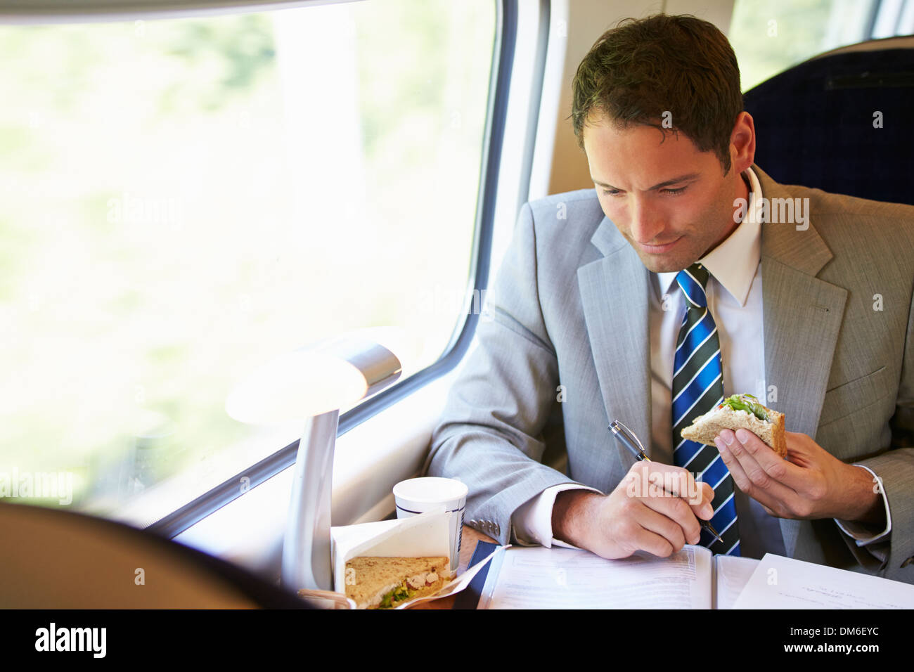 Imprenditore mangiare panino sul viaggio In treno Foto Stock