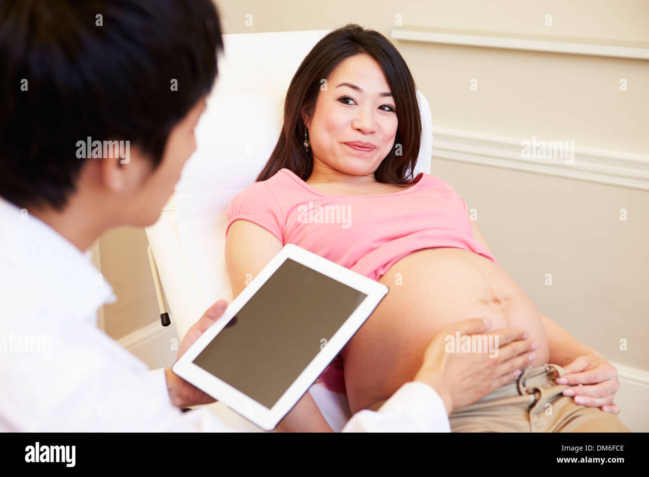 Medico utilizzando digitale compressa in riunione con donna in stato di gravidanza Foto Stock