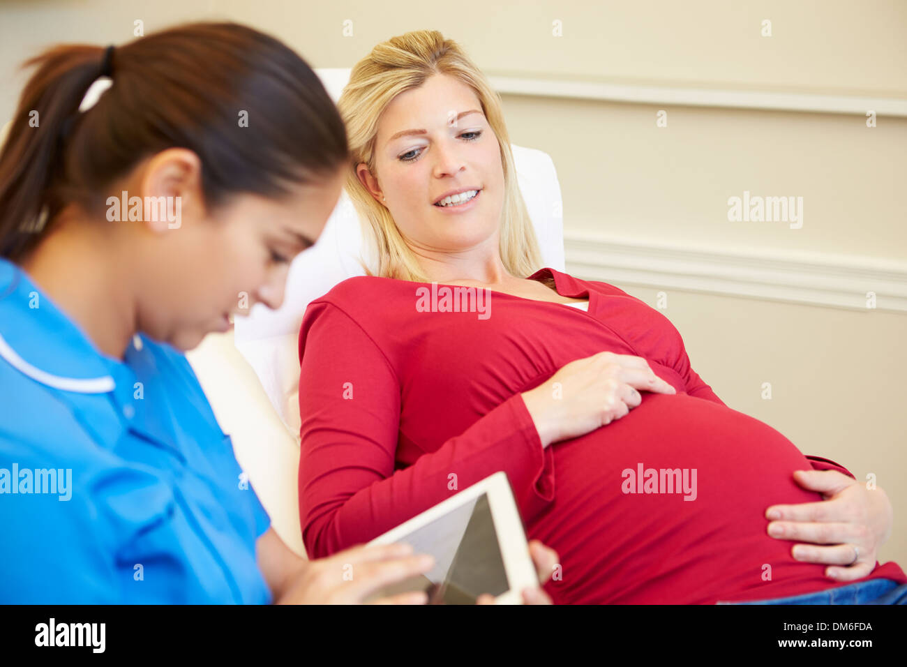 Infermiere con tavoletta digitale in riunione con donna in stato di gravidanza Foto Stock