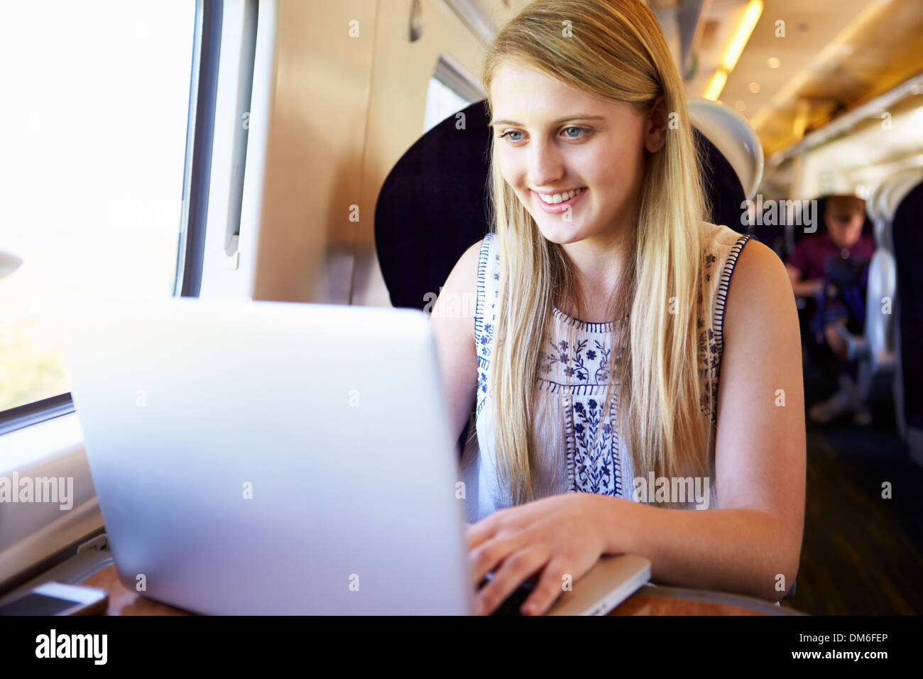 Ragazza adolescente utilizzando laptop in viaggio in treno Foto Stock