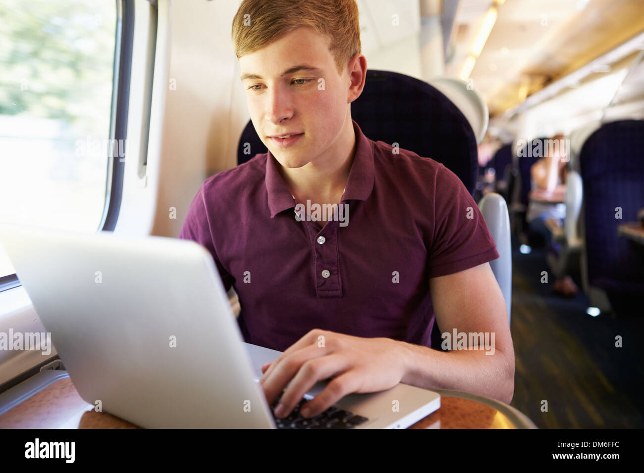 Giovane uomo utilizzando laptop in viaggio in treno Foto Stock