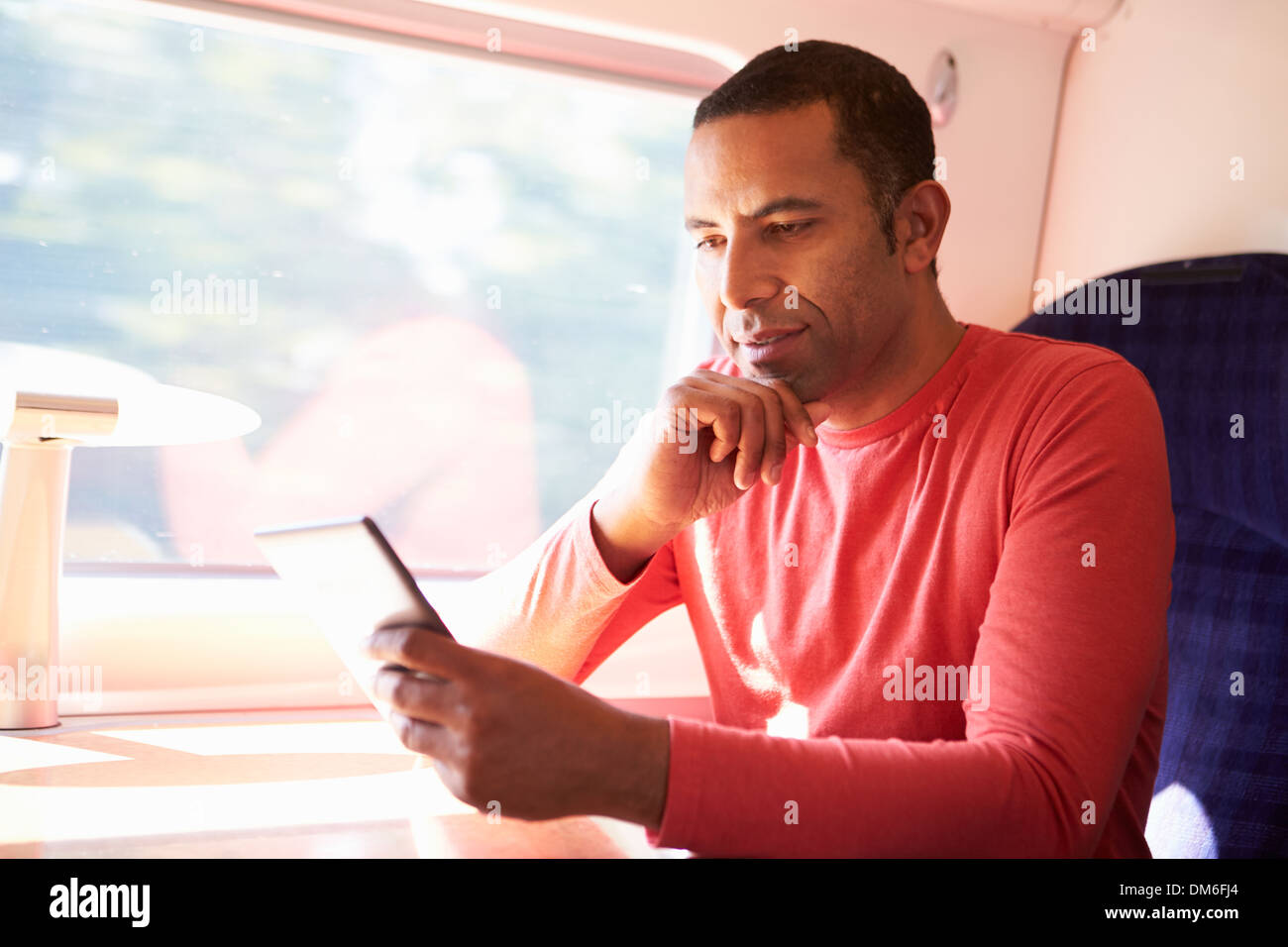 L uomo e la lettura di un libro sul treno Foto Stock