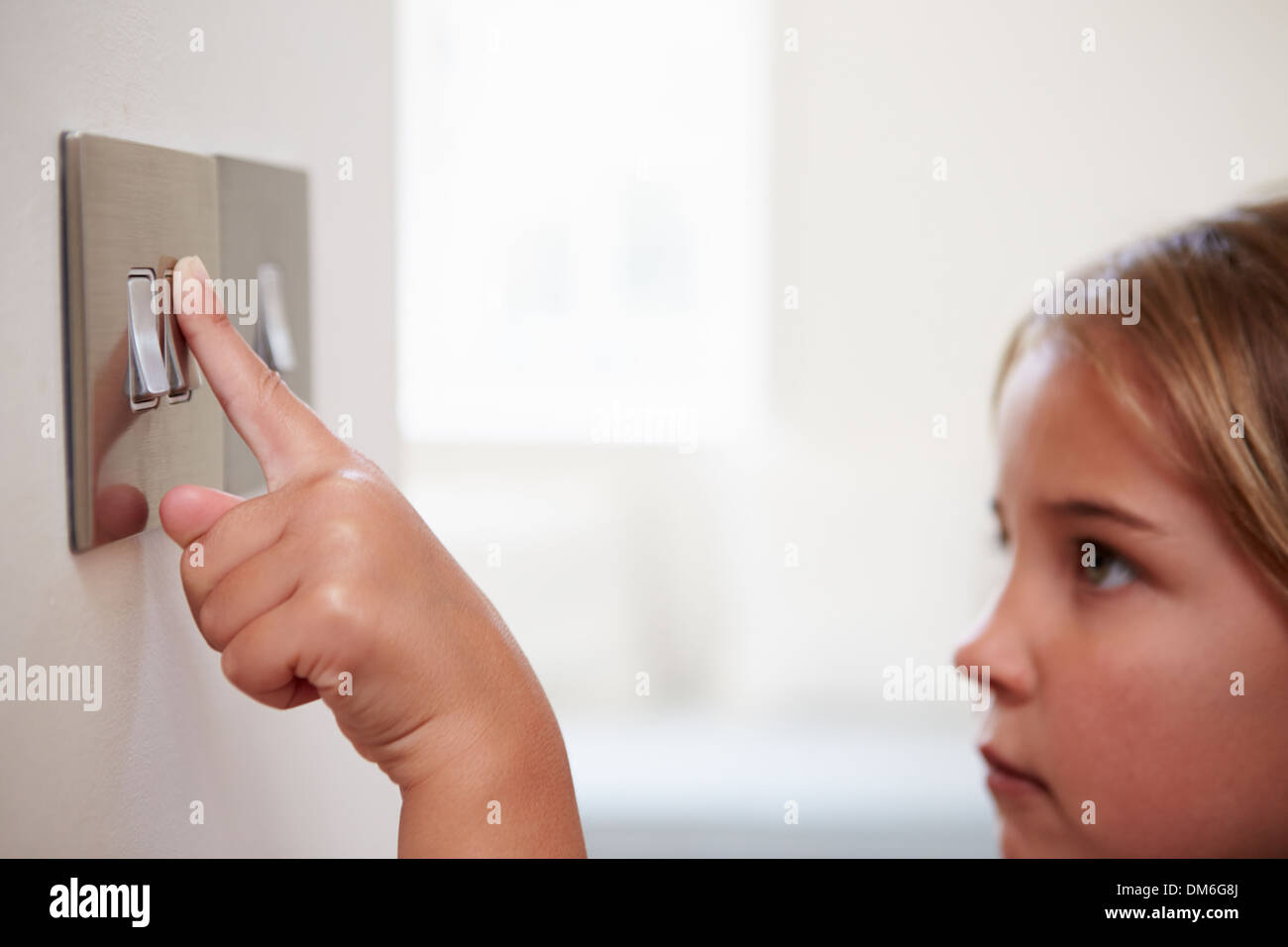 Ragazza giovane spegnendo la spia interruttore Foto Stock