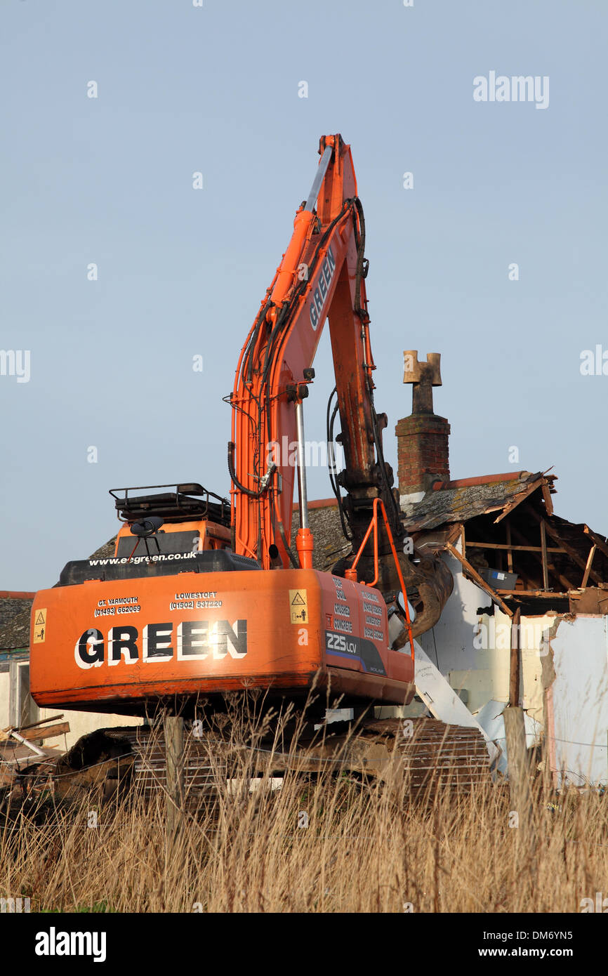 Un escavatore cingolato per demolizione Doosan Solar 225 LC-V con un gancio/benna per demolizione per impieghi gravosi che demolisce un edificio a Norfolk nel Regno Unito. Escavatore idraulico cingolato arancione che utilizza una benna per demolizione per abbattere una struttura industriale bassa, con macerie e detriti che cadono a terra. Macchinari pesanti per l'edilizia in fase di ristrutturazione sotto un cielo nuvoloso. Foto Stock