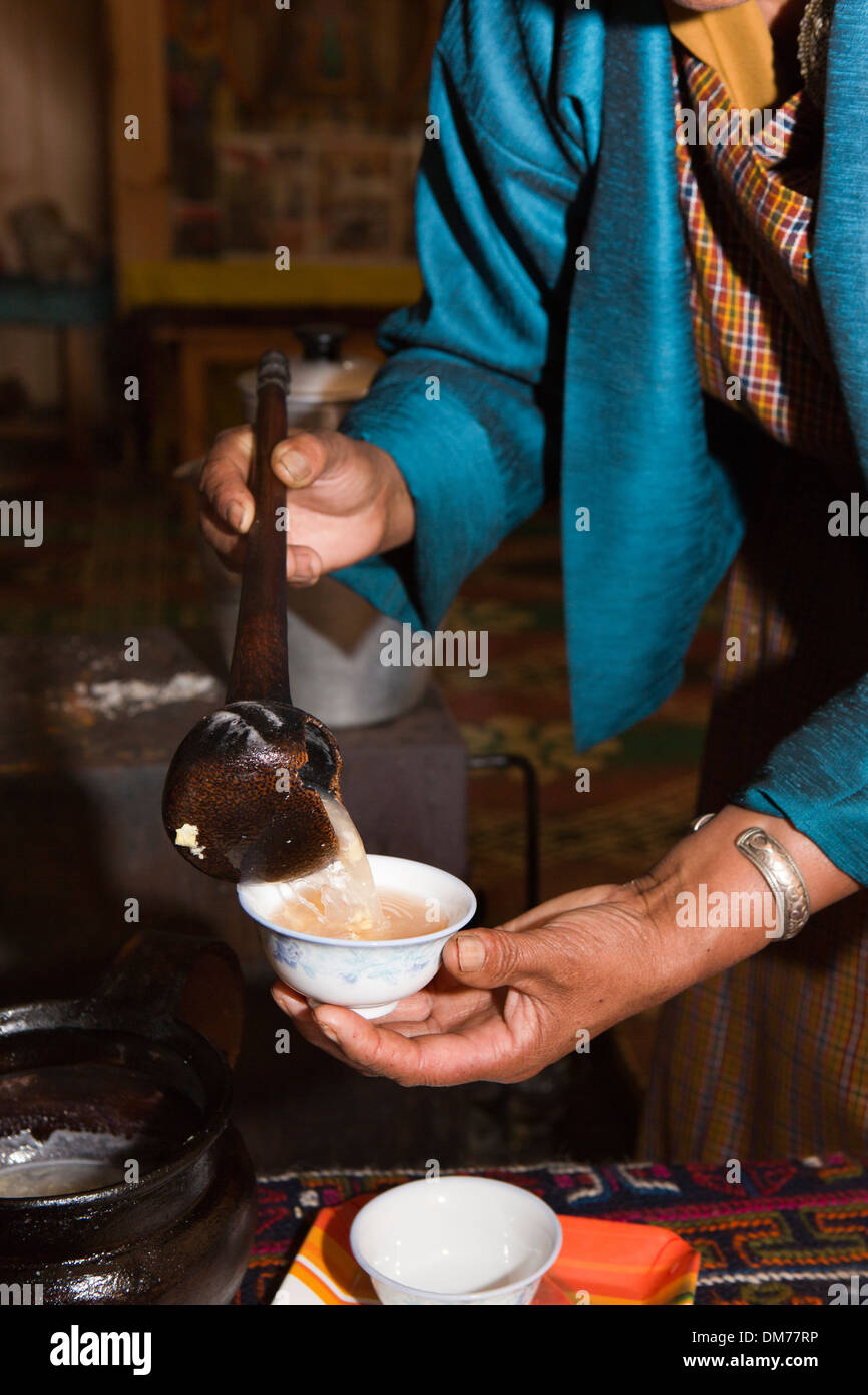 Il Bhutan, Bumthang Valley, donna che serve hot arra (locale di vino di riso) con uovo bere Foto Stock