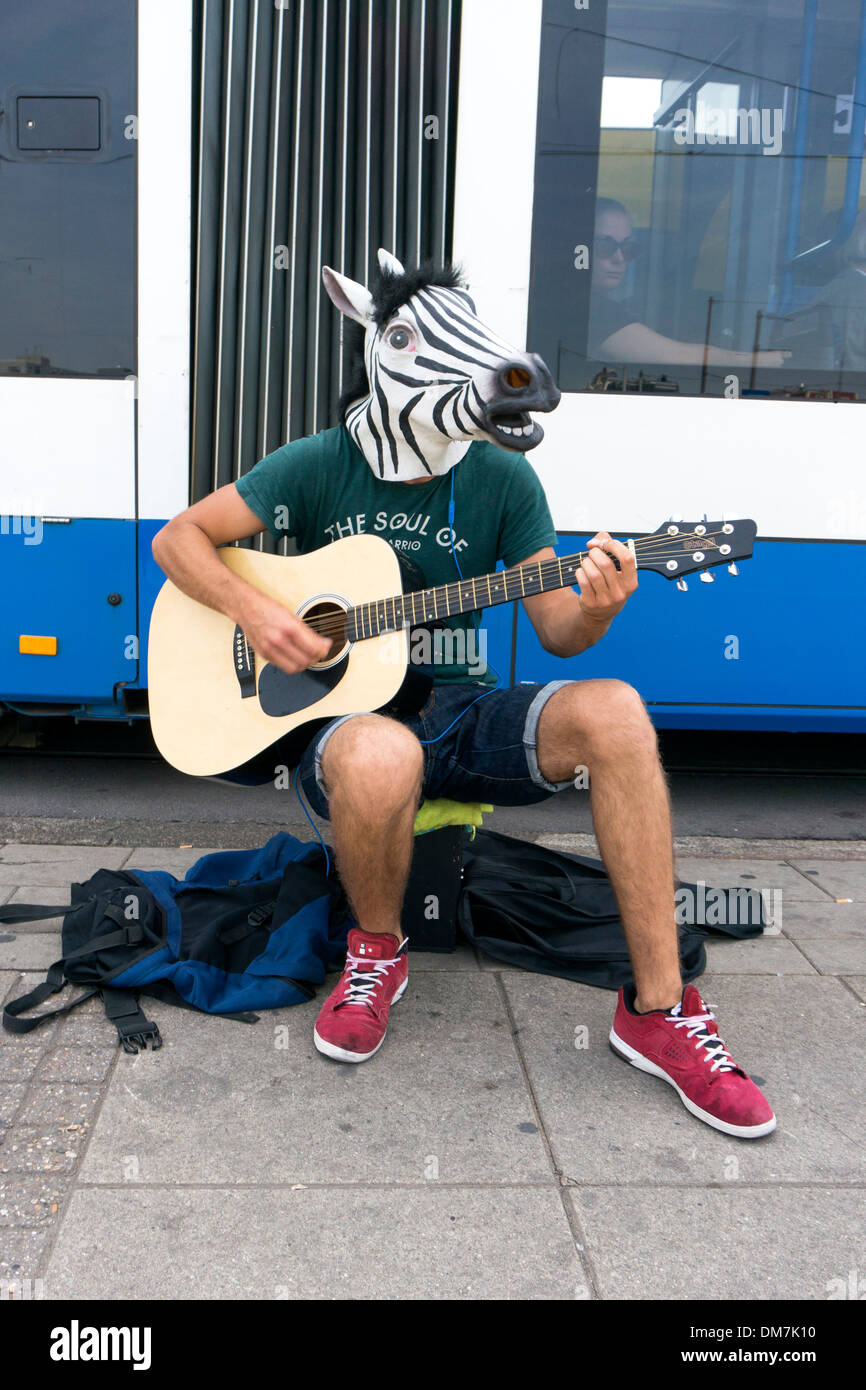 Suonare la chitarra busker in zebra travestimento tenta di fare un po' di soldi nella parte anteriore di un tram in Amsterdam Foto Stock