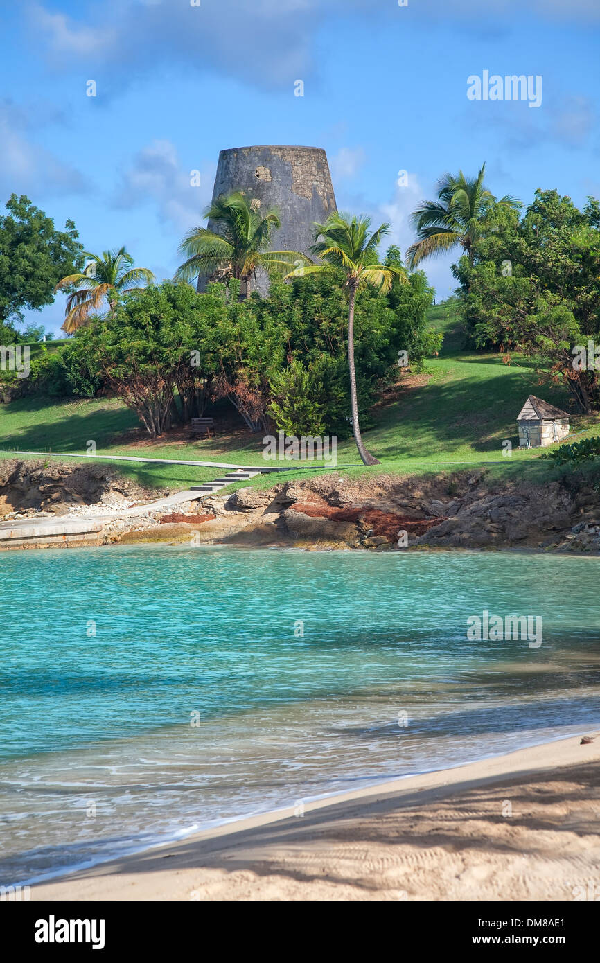 Un mulino per lo zucchero e una piccola spiaggia sull'isola caraibica di Antigua. Foto Stock