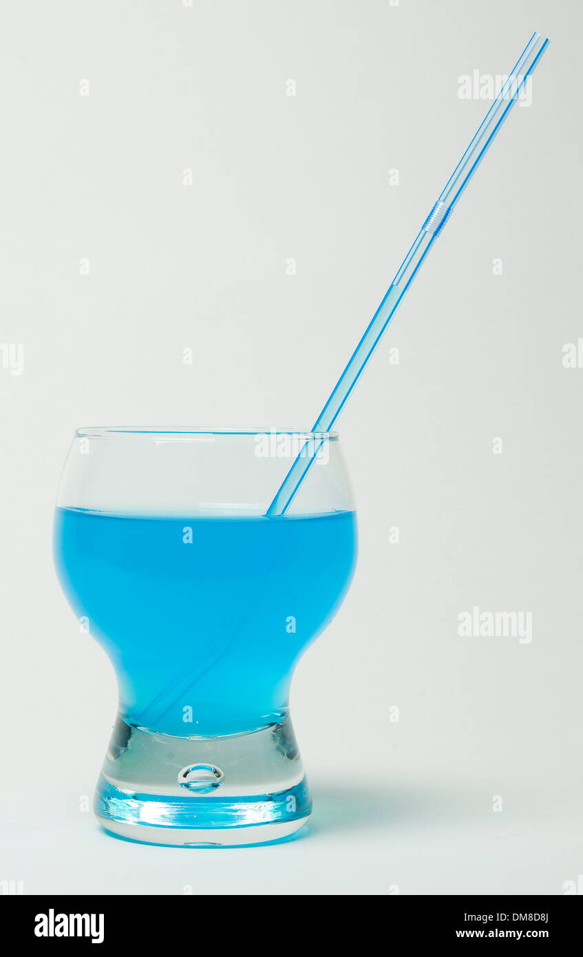 Vetro con una cannuccia e un liquido di colore blu su sfondo bianco Foto Stock