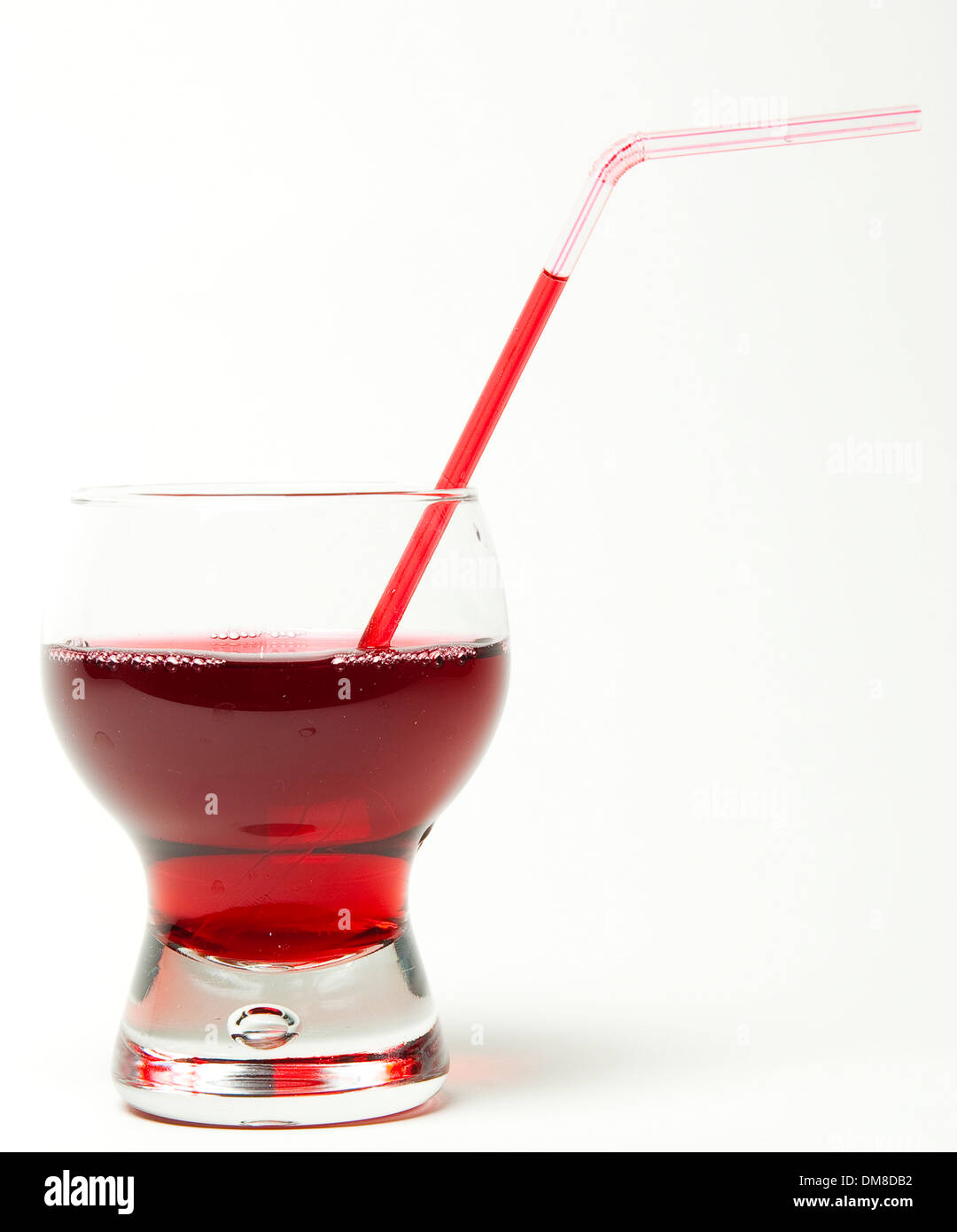 Vetro con una cannuccia e un liquido rosso su sfondo bianco Foto Stock