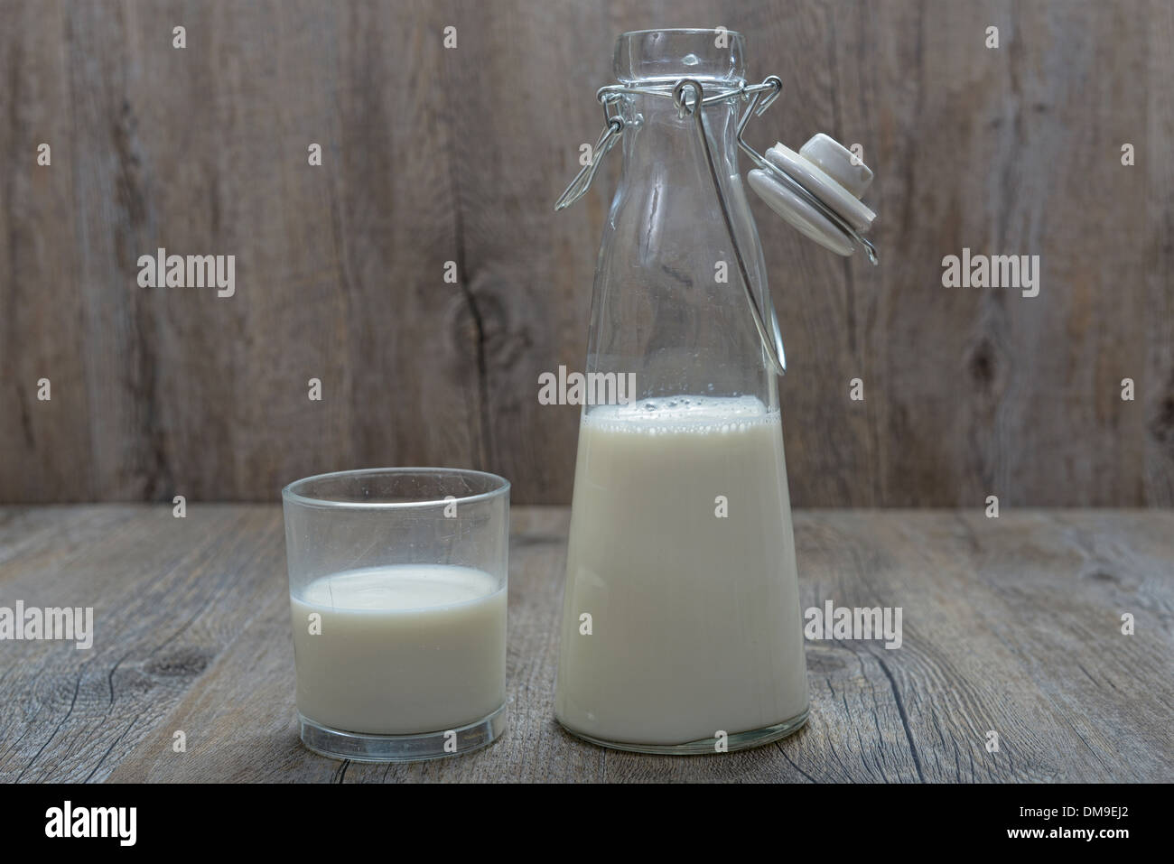 Bottiglia di latte con un bicchiere su un tavolo di legno Foto Stock