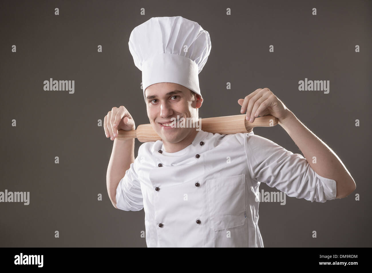 Ritratto di chef sorridente con il mattarello isolato su sfondo grigio Foto Stock