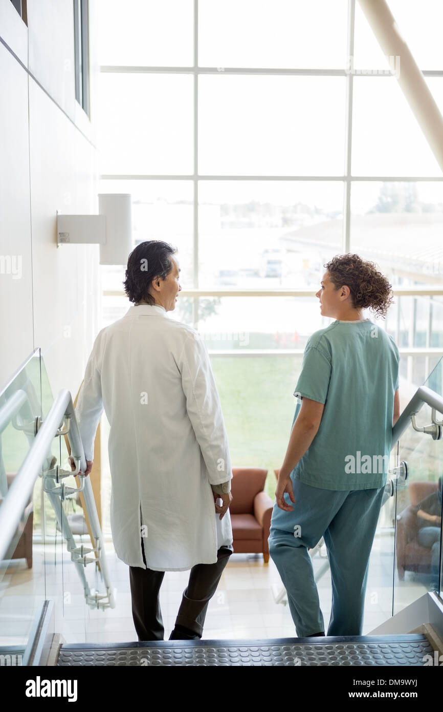 Medico e infermiere a conversare mentre si cammina giù per le scale in Hospita Foto Stock