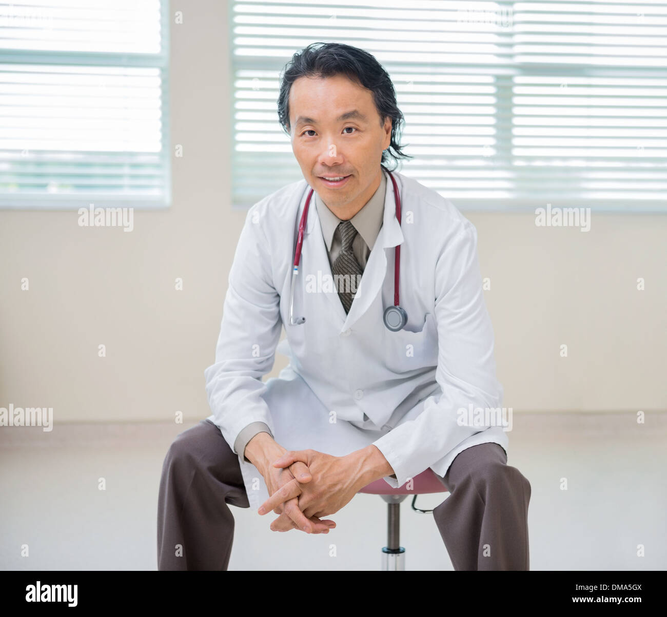 Medico seduto alla stanza di ospedale con paziente in background Foto Stock