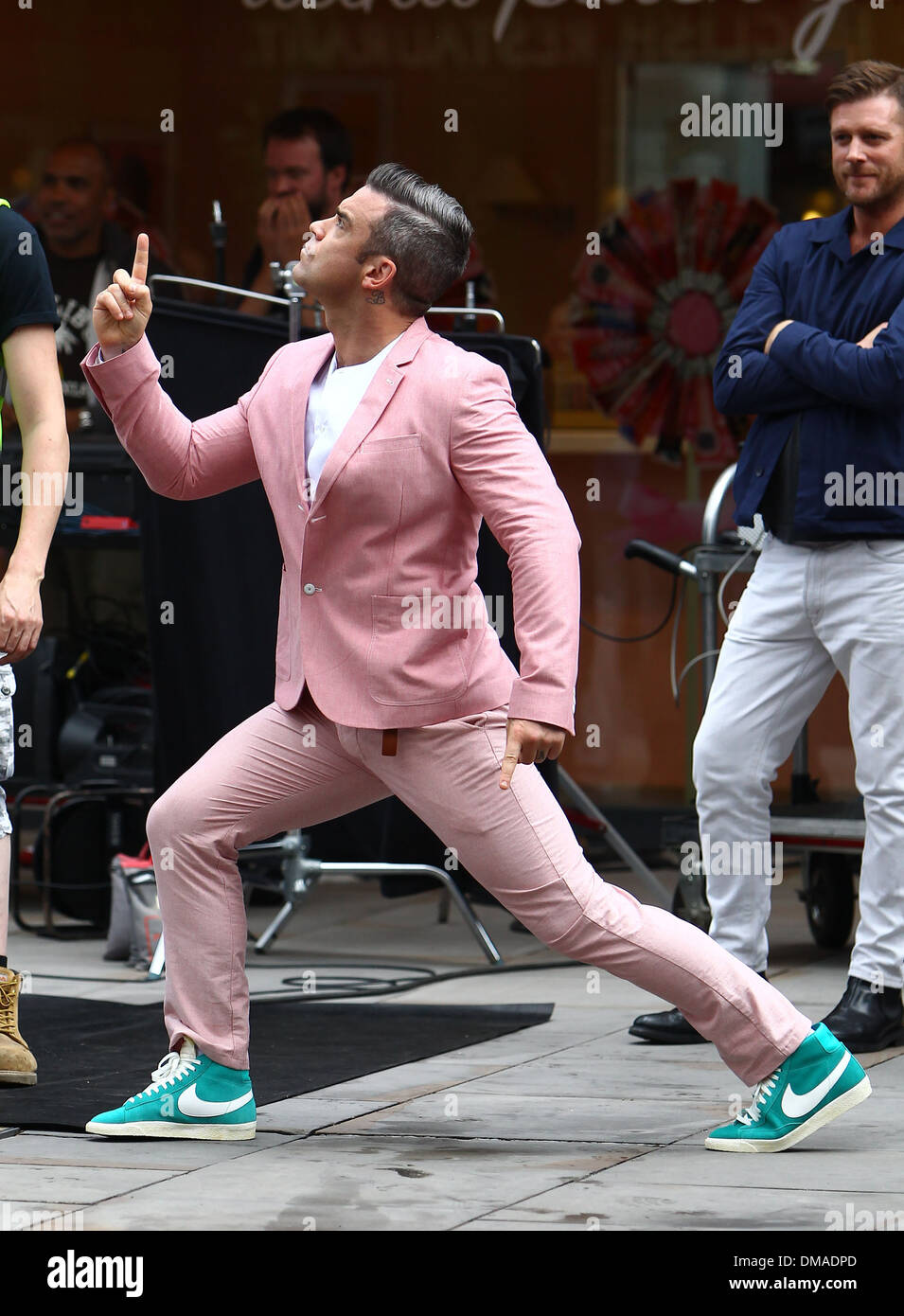 Robbie Williams esegue una routine di breakdance in un abito rosa e turchese  Nike high-top scarpe come egli film le scene per la sua nuova Foto stock -  Alamy