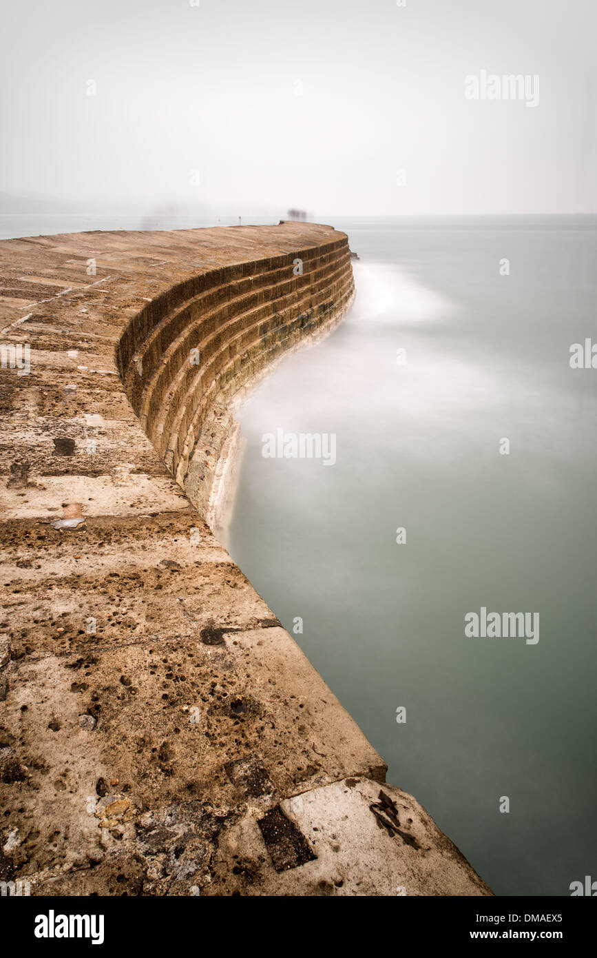 Una lunga esposizione paesaggio astratto Lyme Regis Cobb per la difesa del mare Foto Stock