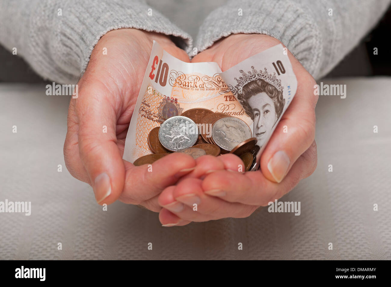 Primo piano mano di uomo persona mani che tengono in mano denaro inglese banconota da dieci sterline e monete in contanti risparmi Inghilterra Regno Unito Regno Unito Gran Bretagna Foto Stock