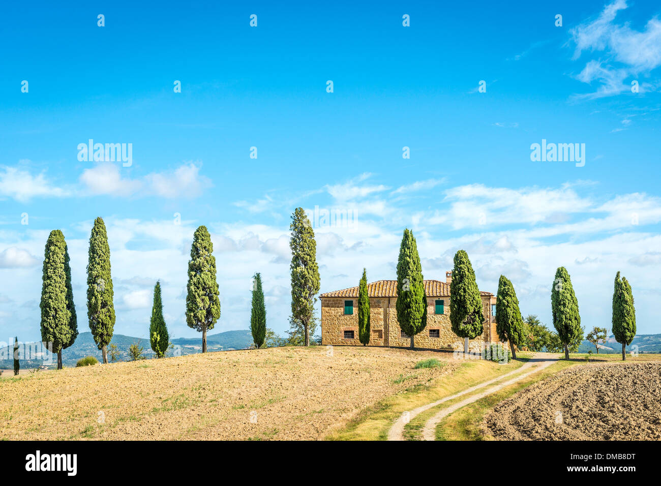 Tipica casa in Toscana, Italia, con cipressi, campo e cielo blu Foto Stock