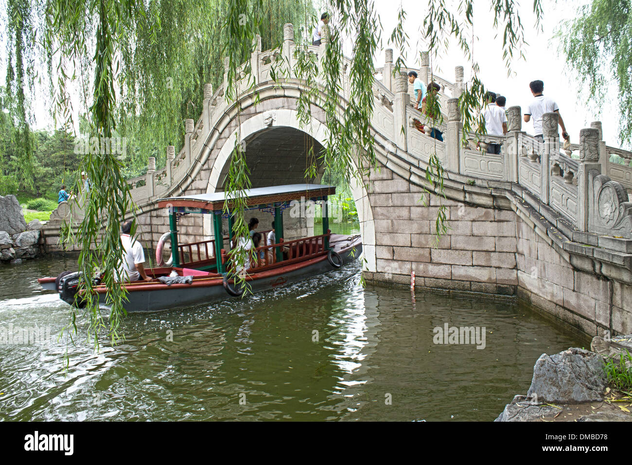 Cinese gita in barca di un parco. Andare in barca attraverso un ponte di arco Foto Stock