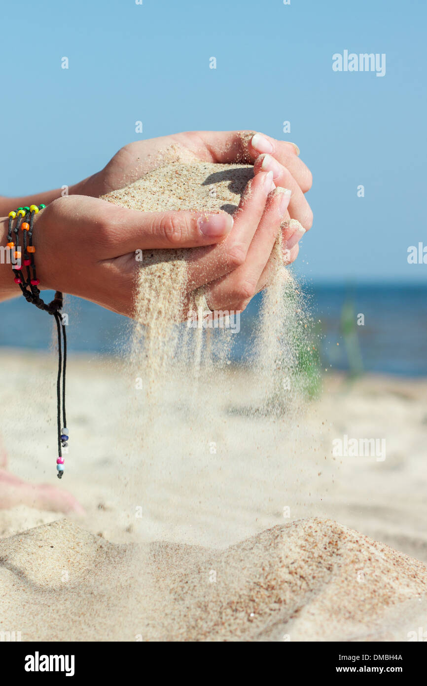 "Donna di mani mani sabbia versatore 'sandy beach' estate mare skyline Foto Stock