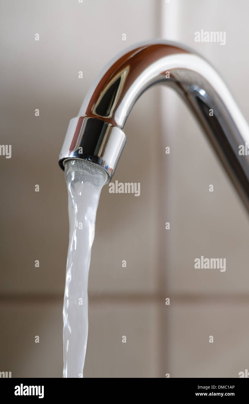 L'immagine verticale di un rubinetto con acqua che scorre normalmente Foto Stock