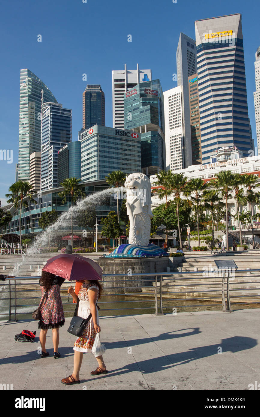 I TURISTI GUARDANDO LA SCULTURA MERLION, simboleggia la SINGAPORE, ai piedi delle torri di uffici nel quartiere finanziario, il quartiere centrale degli affari, SINGAPORE Foto Stock