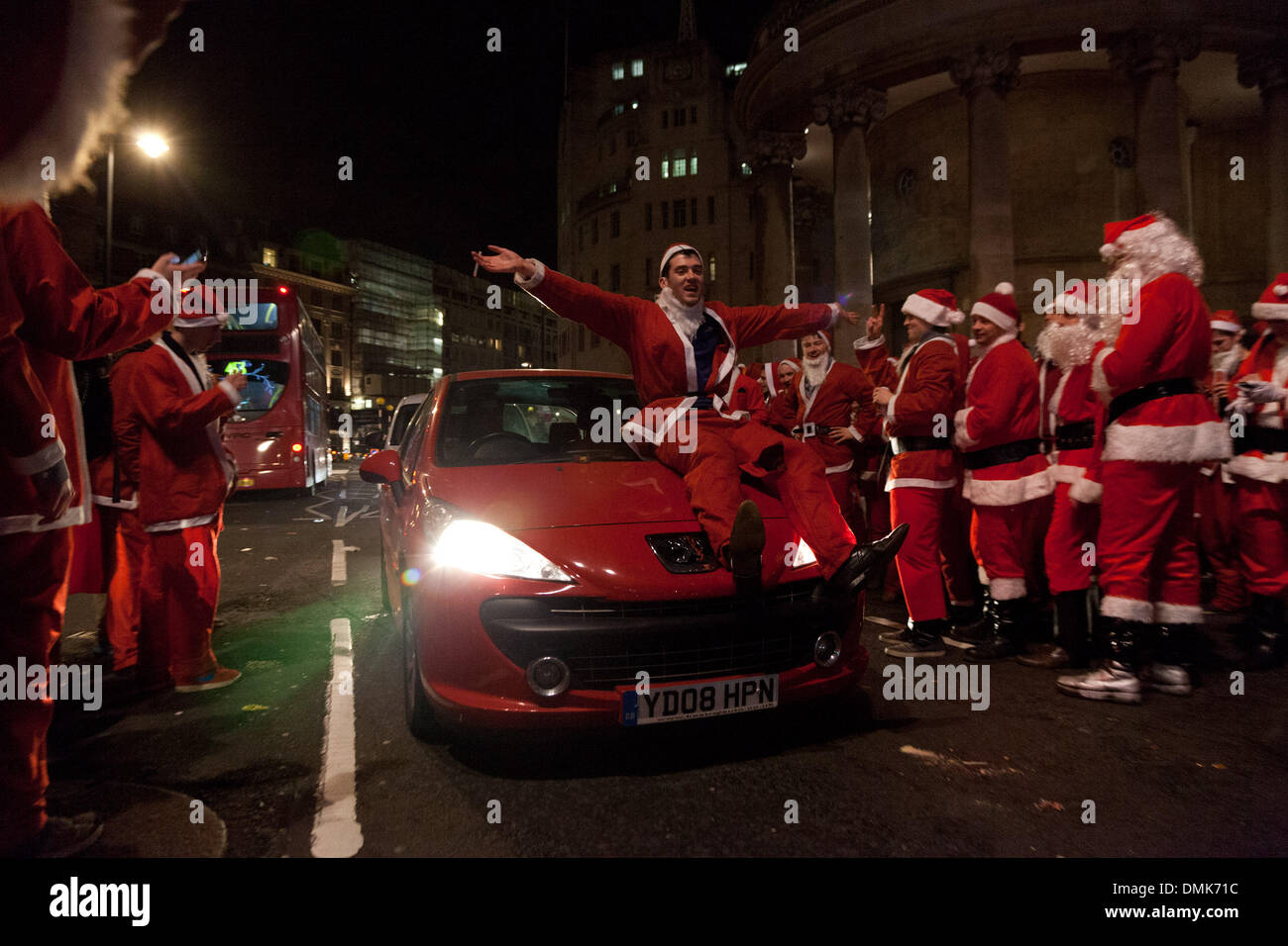 Londra, Regno Unito. 14 dicembre 2013 un partecipante dell'annuale Santa con attacchi di evento un giro mentre partying fuori BBC Broadcasting House in Portland Place. Credito: Nelson pereira/Alamy Live News Foto Stock