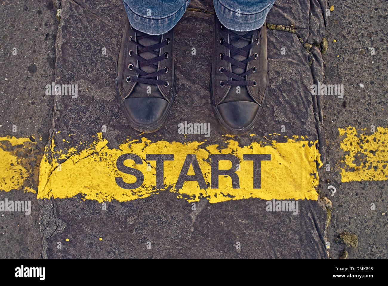 Sneakers maschio su asfalto con la linea gialla e titolo Inizio. Foto Stock