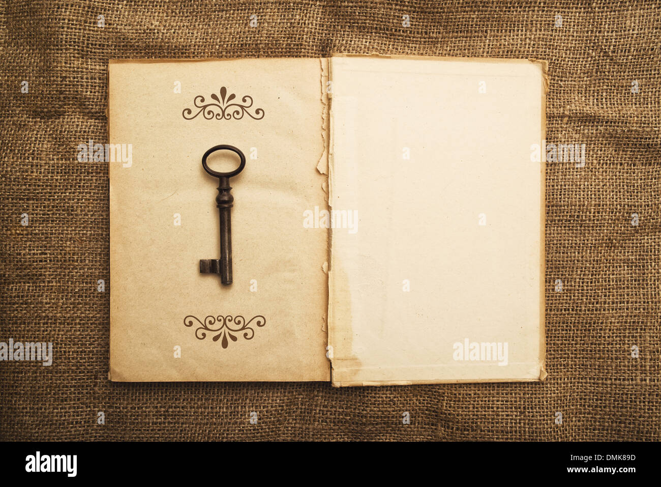 Vintage libro aperto con la vecchia carta grunge textured pagine e chiave arrugginito Foto Stock