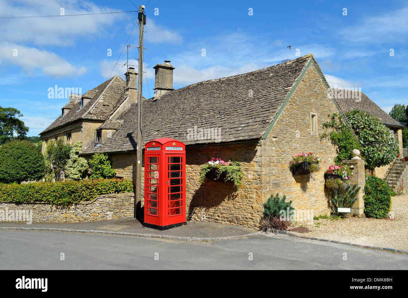 Color miele case in pietra e un telefono rosso scatola in un villaggio in Cotswolds in Inghilterra rurale. Foto Stock