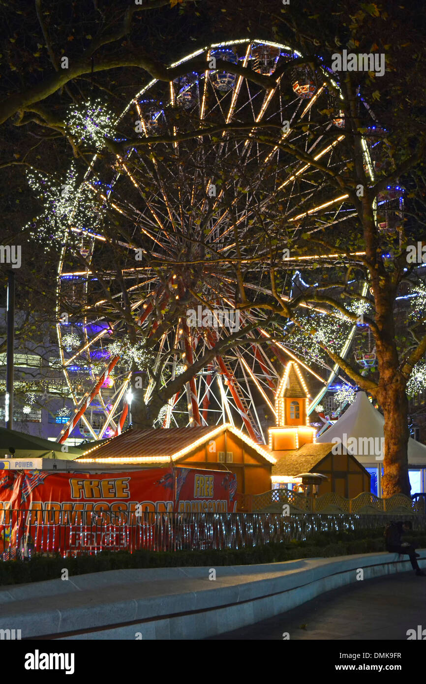 Grande ruota panoramica Ferris al di là di inverno alberi a Leicester Square fiera di Natale di notte Foto Stock