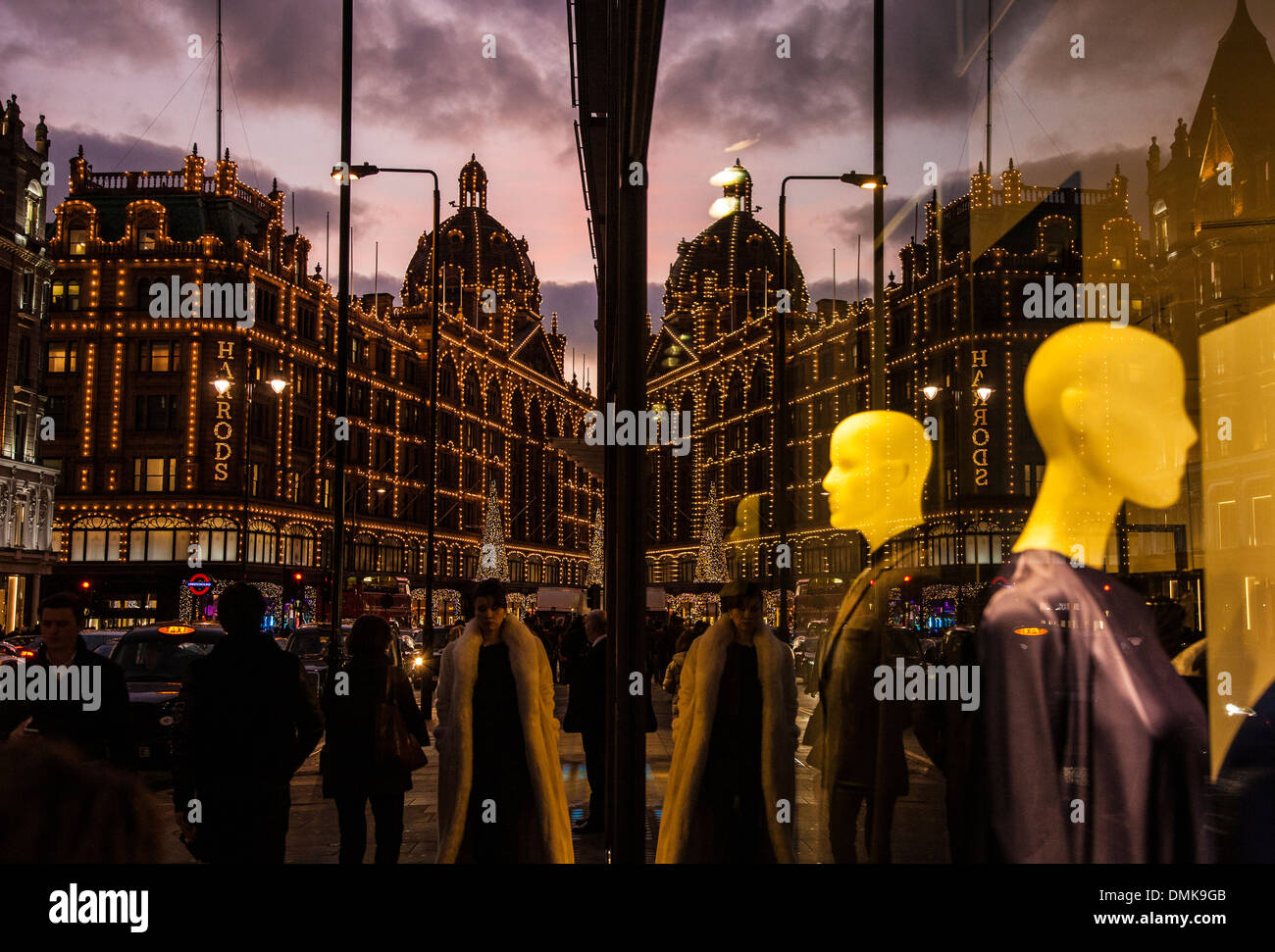 I grandi magazzini Harrods, Knightsbridge, Londra con le luci di Natale sul riflesso in un vicino negozio finestra. Foto Stock