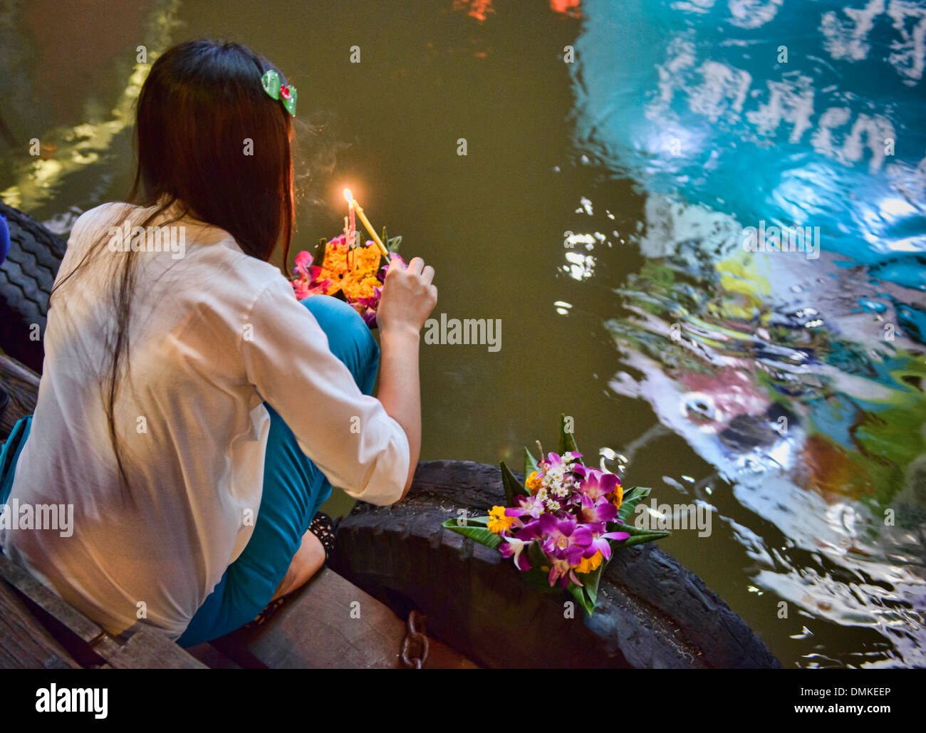 Giovane donna rilascia una offerta flottante durante Loy Kratong festival a Bangkok, in Thailandia Foto Stock