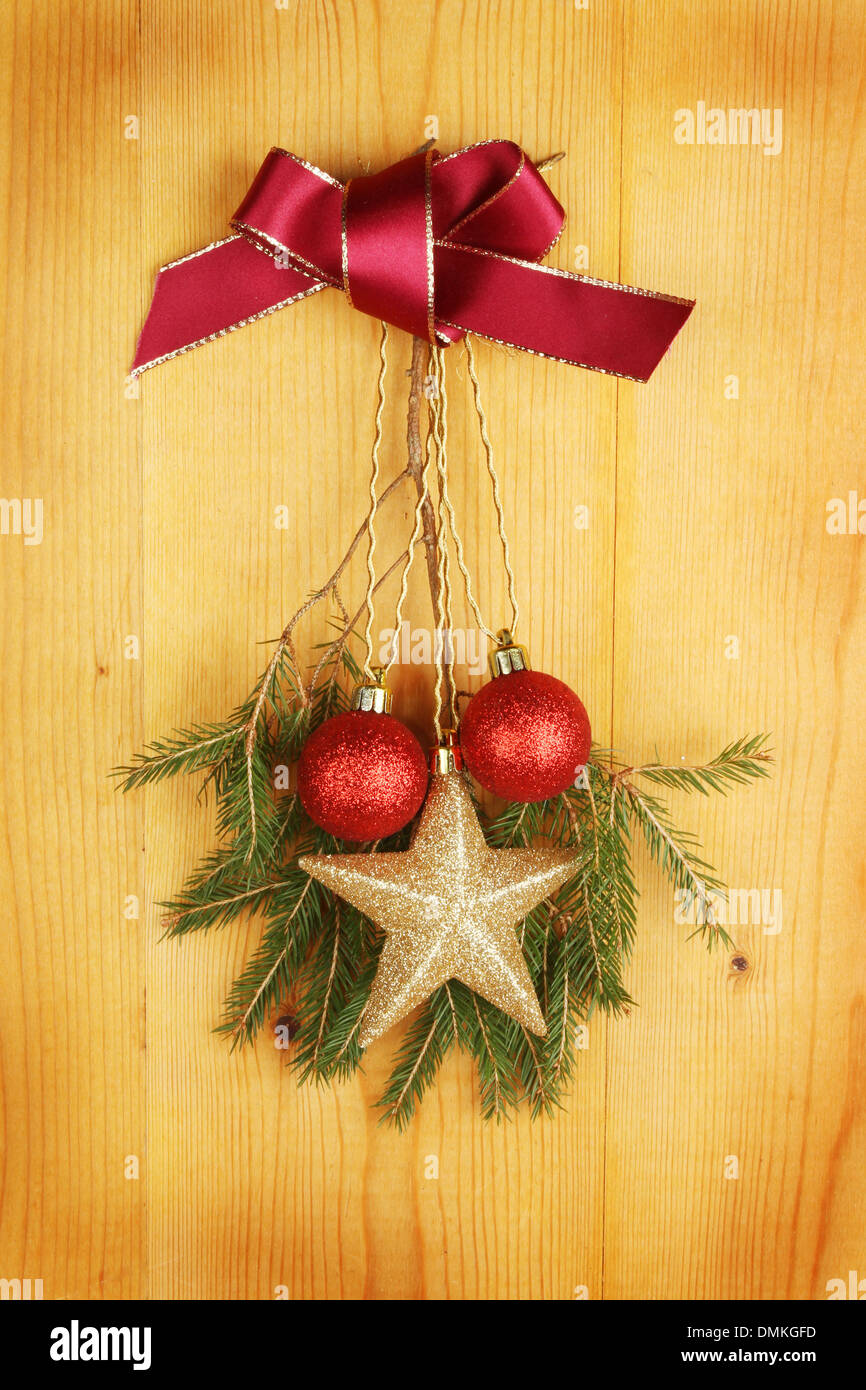 Decorazione di natale di un fiocco rosso, albero di Natale ramo e baubles appeso su un pannello di legno Foto Stock