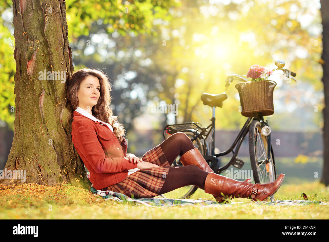 Giovane bella femmina con bicicletta seduti su un prato verde e rilassante in un parco Foto Stock