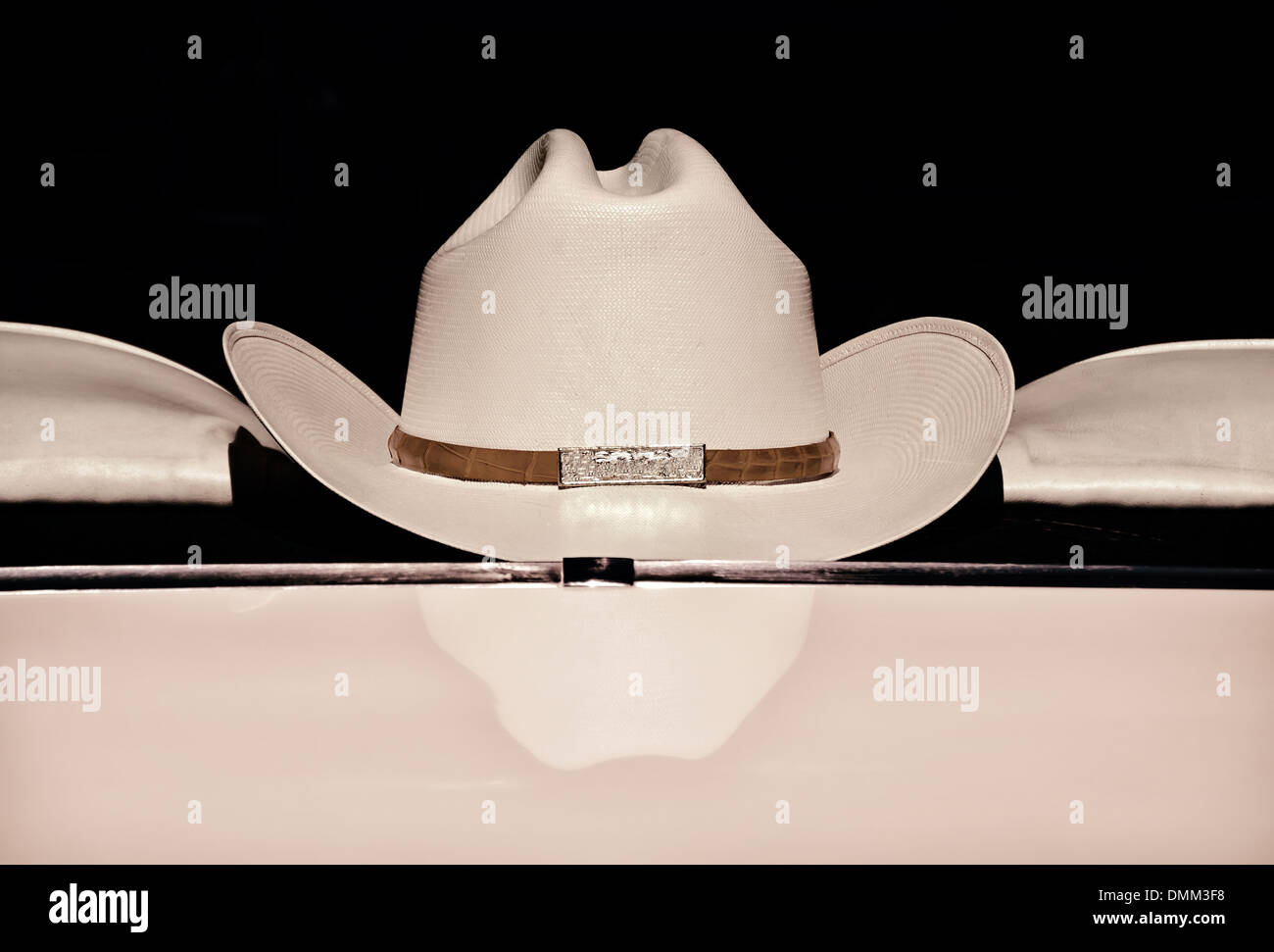 Il cappello da cowboy visualizzato sul retro di un finestrino contro uno sfondo scuro, colore seppia Foto Stock