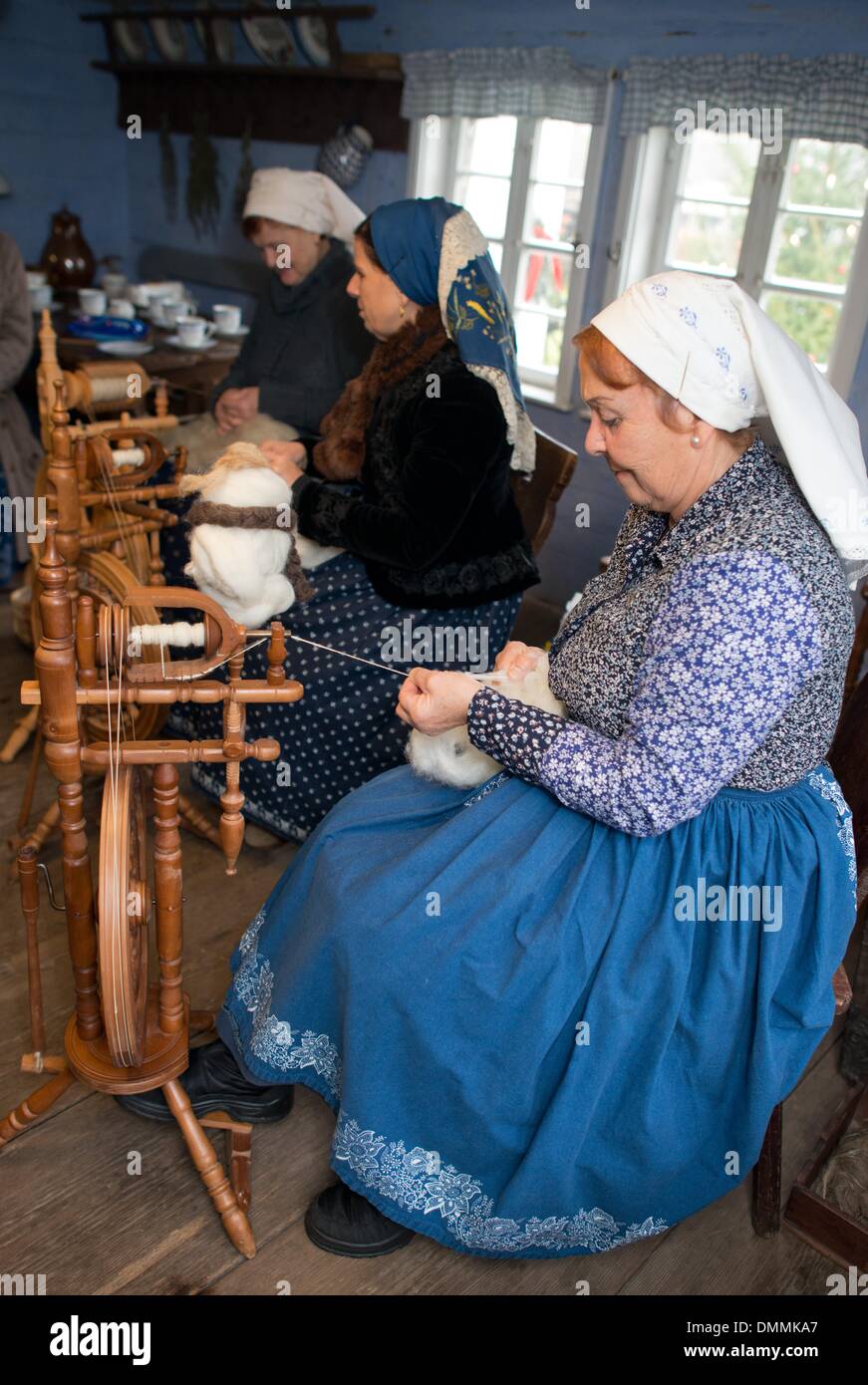 Lehde, Germania. L'8 dicembre, 2013. Le donne in abbigliamento tradizionale dalla regione Spreewald sedersi dietro le ruote di filatura lavorazione di lana di pecora in open-air museum in Lehde, Germania, 8 dicembre 2013. Il museo dispone di tre insiemi completi di Wendish fattorie che introducono i visitatori alla storia locale, i modi di vita, abbigliamento tradizionale e tipico craftswork nei locali della regione Spreewald. Foto: Patrick Pleul/ZB/dpa/Alamy Live News Foto Stock