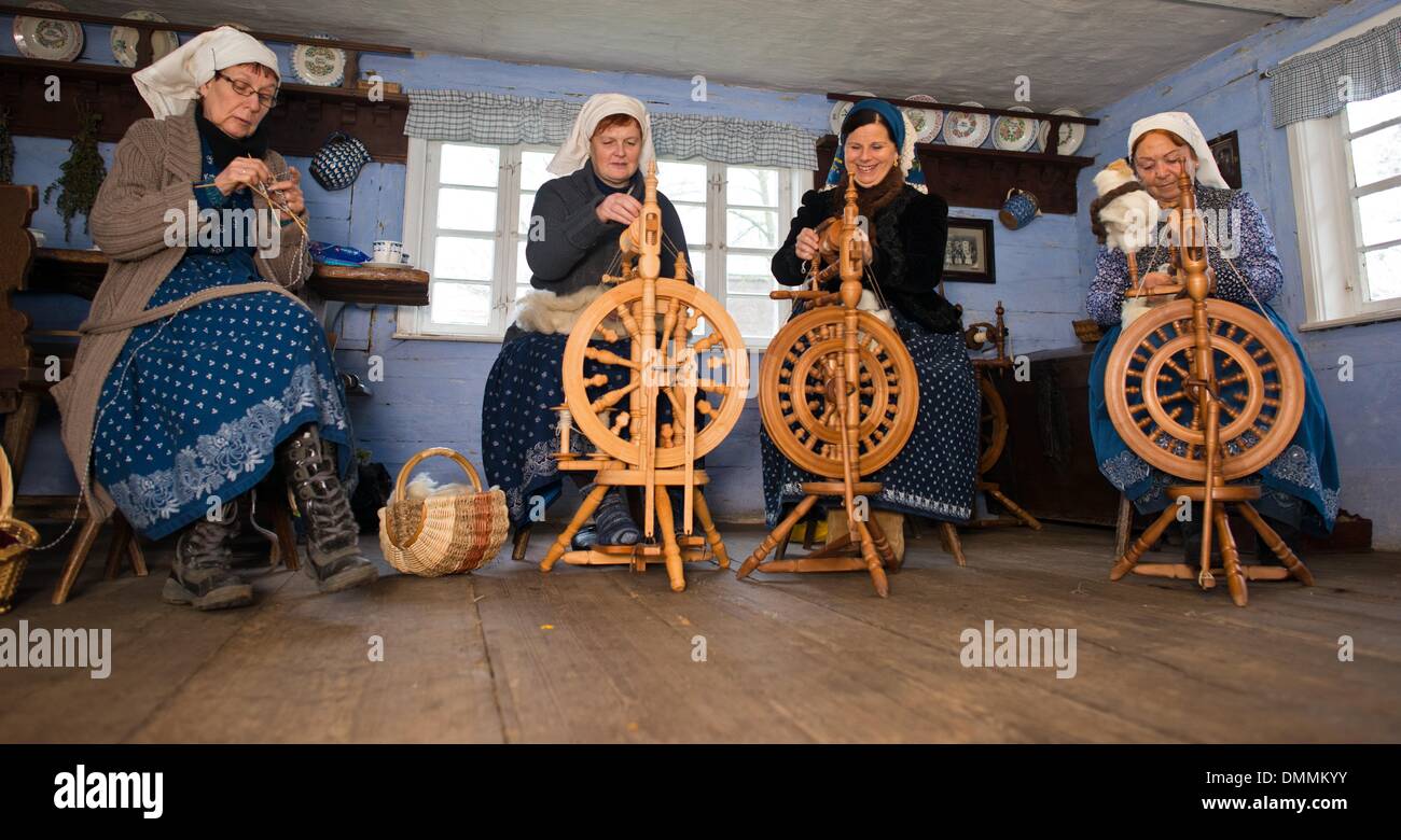 Lehde, Germania. L'8 dicembre, 2013. Le donne in abbigliamento tradizionale dalla regione Spreewald sedersi dietro le ruote di filatura lavorazione di lana di pecora in open-air museum in Lehde, Germania, 8 dicembre 2013. Il museo dispone di tre insiemi completi di Wendish fattorie che introducono i visitatori alla storia locale, i modi di vita, abbigliamento tradizionale e tipico craftswork nei locali della regione Spreewald. Foto: Patrick Pleul/ZB/dpa/Alamy Live News Foto Stock