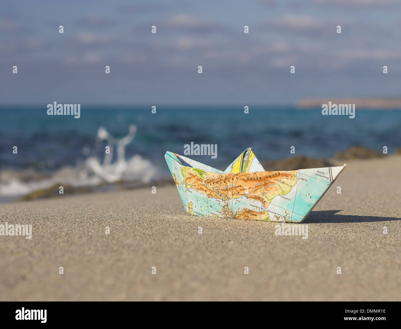 Spagna, Formentera, piccola barca di carta piegata di una mappa che giace sulla spiaggia sabbiosa a riva Foto Stock