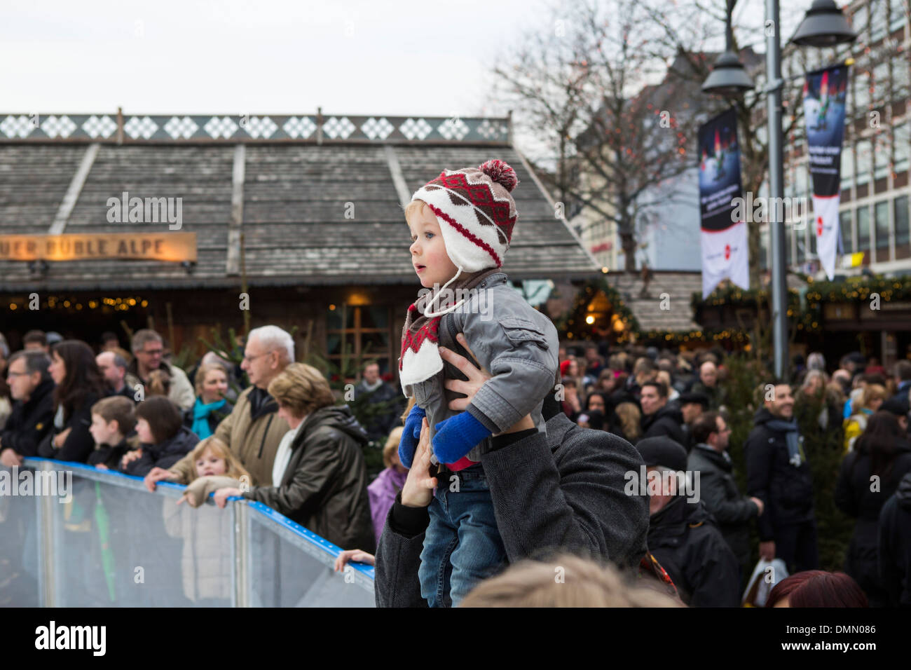 Mercatino di Natale di Colonia, ragazzino sulle spalle del padre che guarda il pattinaggio in Altstadt (città vecchia) Foto Stock