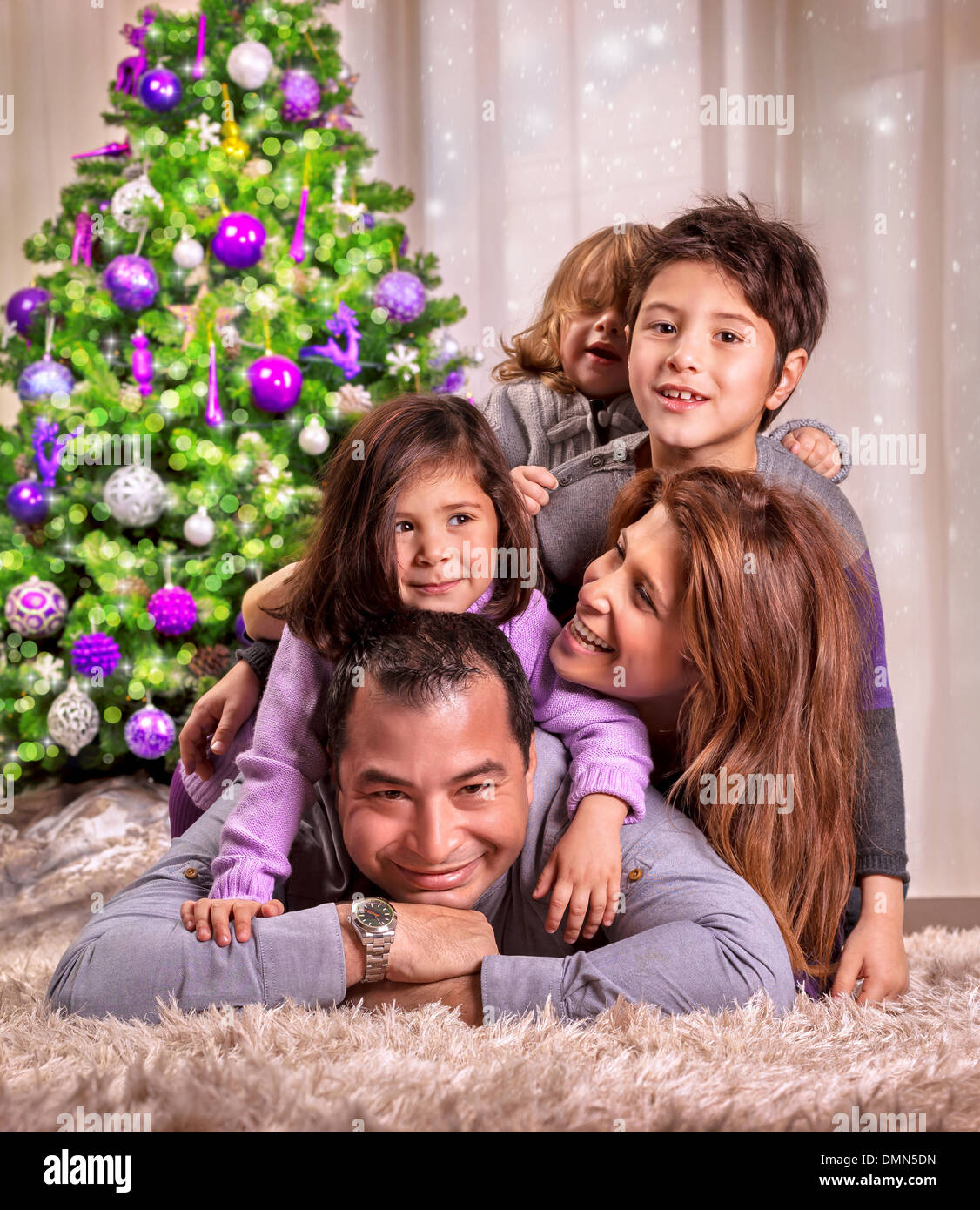 Ritratto di felice famiglia araba sdraiati vicino al bellissimo albero di Natale decorato, celebrando la vacanza a casa Foto Stock