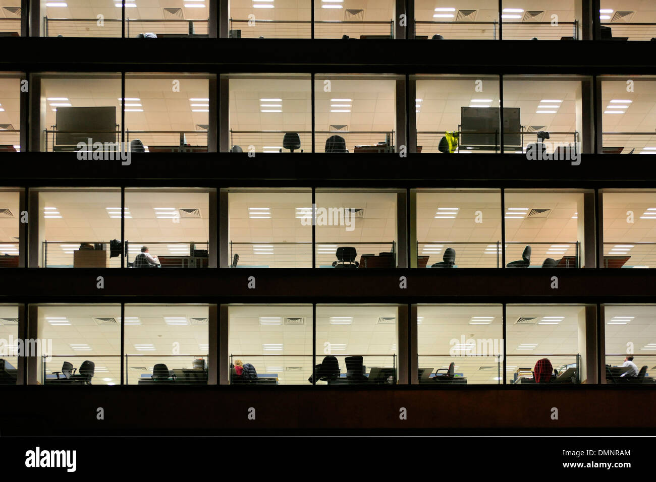 Blocco ufficio con una facciata di vetro che mostra le persone a loro scrivanie Foto Stock