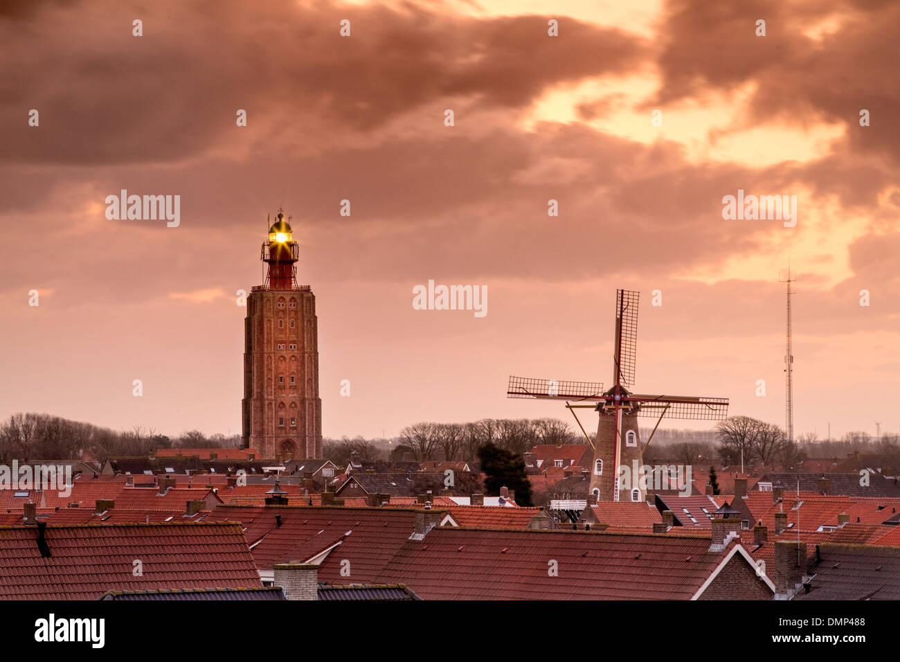 Paesi Bassi, Westkapelle, vista sulla ex chiesa torre, ora casa leggera, mulino a vento e il centro del villaggio di sunrise Foto Stock