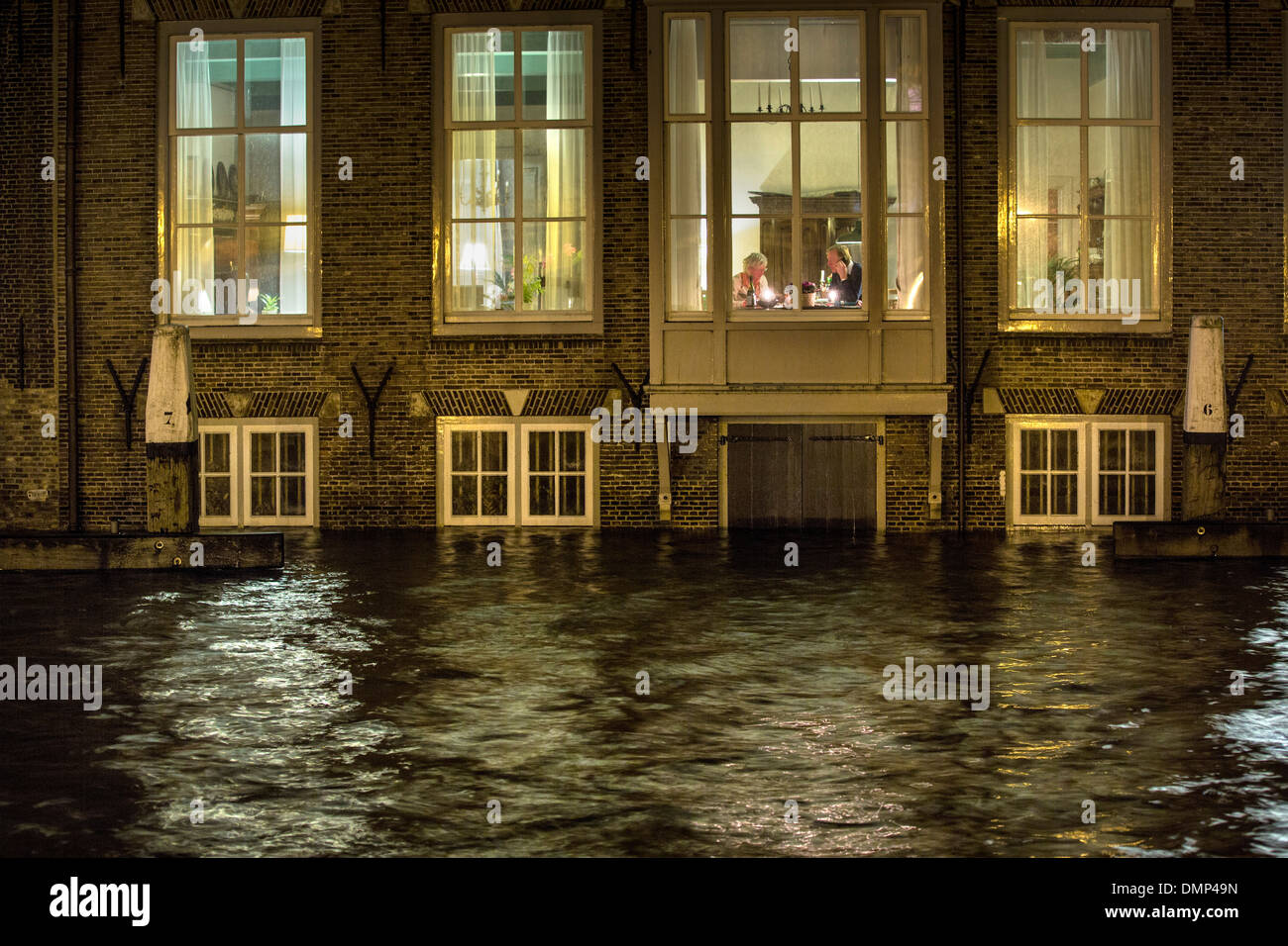 Paesi Bassi, Dordrecht, inondazioni nella storica citta' interna. Coppia senior dines sul primo piano, mentre il seminterrato è sotto l'acqua Foto Stock