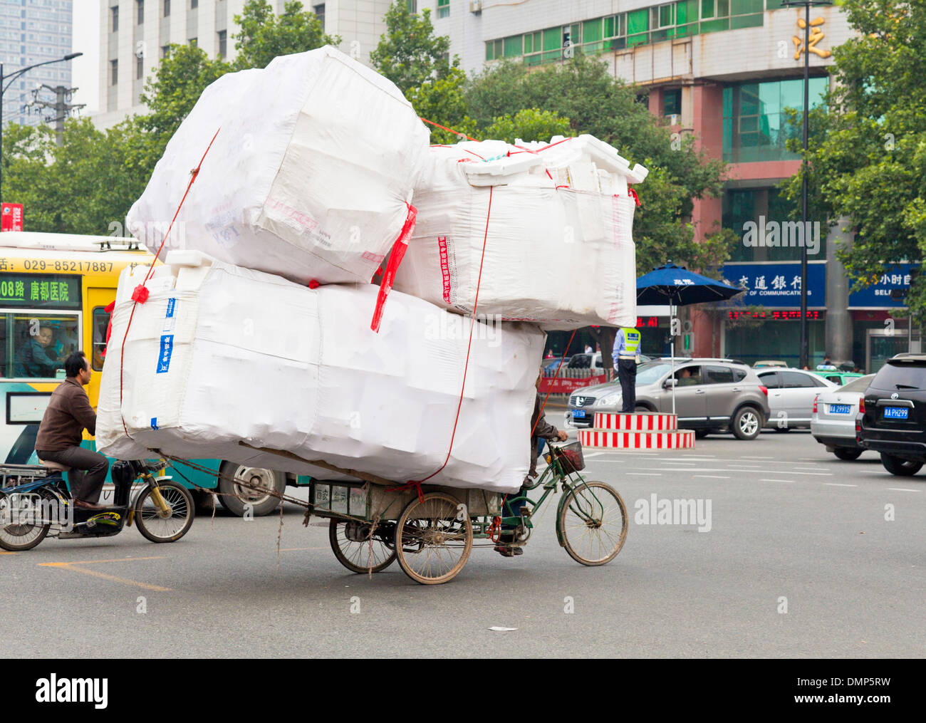 Uomo in bicicletta carrello trasporta un carico di scatole attraverso una giunzione occupato Xian, Provincia di Shaanxi, PRC Repubblica Popolare di Cina Asia Foto Stock