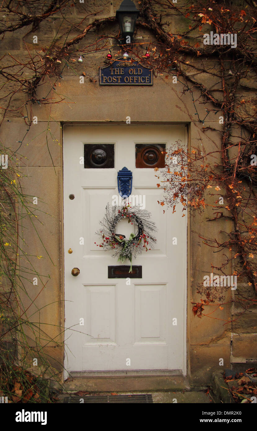 Ghirlanda di Natale appeso sulla porta anteriore della tradizionale paese di lingua inglese cottage, Eyam, Peak District, Derbyshire, Regno Unito Foto Stock