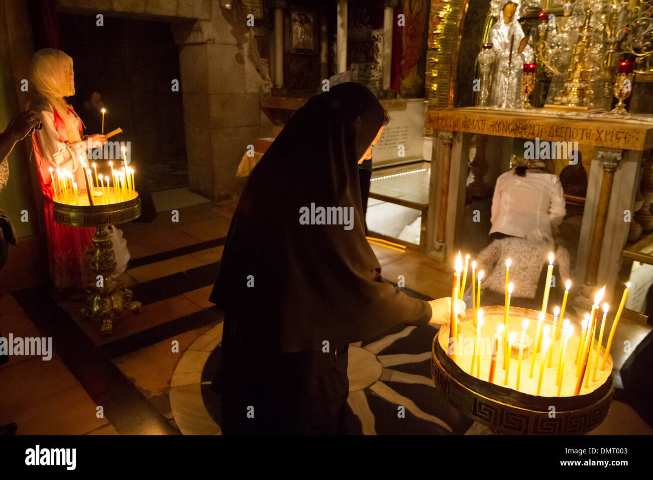 Illuminazione candele di preghiera all interno della chiesa del Santo Sepolcro con pellegrini cristiani di toccare la roccia del Calvario. Foto Stock