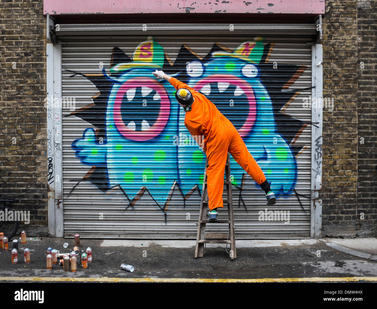 Artista di strada, Ronzo, al lavoro. L'artista utilizza vernici a spruzzo di vernice graffiti giganteschi mostri su una parete - Fashion Street, Londra, Regno Unito Foto Stock