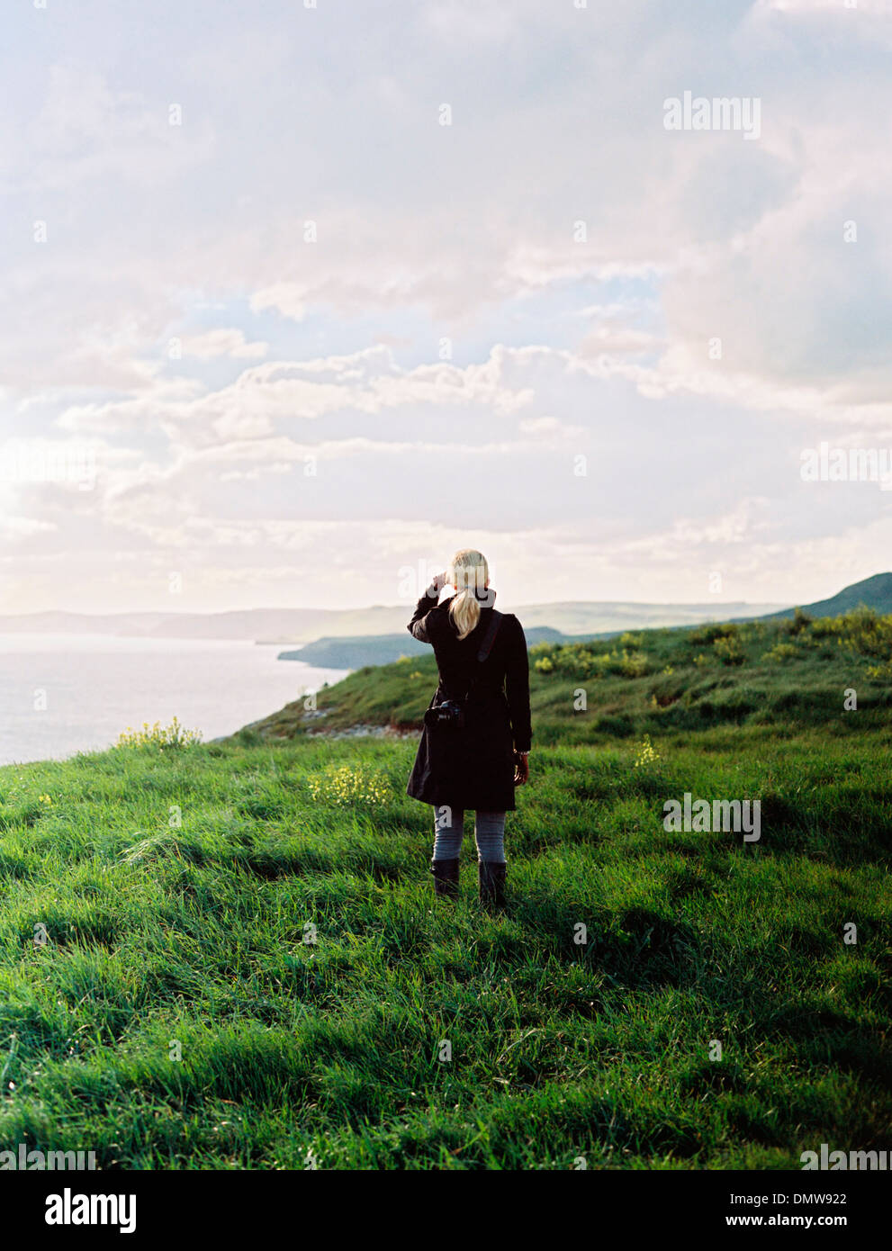 Una donna che guarda lungo il litorale di insenature e scogliere. Foto Stock