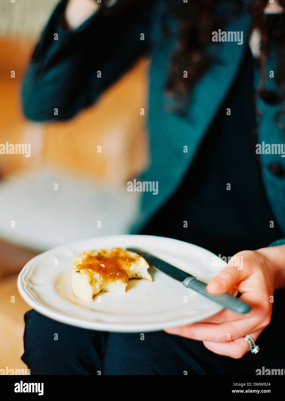 Una persona in possesso di una piastra di fissaggio una mezza mangiata scone con la marmellata. Foto Stock