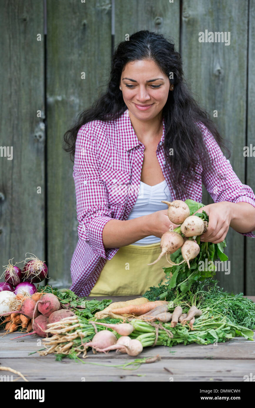 Una donna ordinamento appena raccolto le verdure su una tabella. Foto Stock